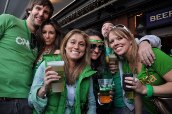 group of men and women wearing green and drinking beer